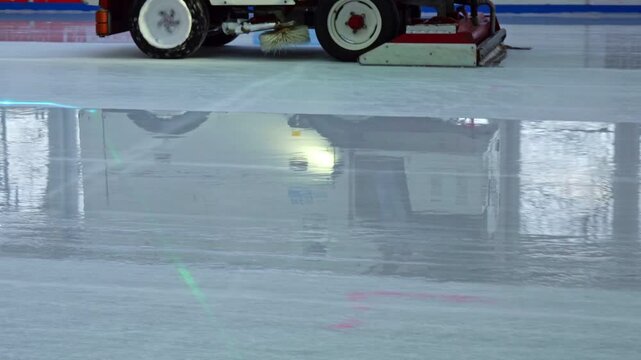 Zamboni cleans and renews icy surface of hockey and skating rink, low angle