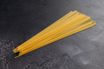 Dry pasta lies on a dark background.