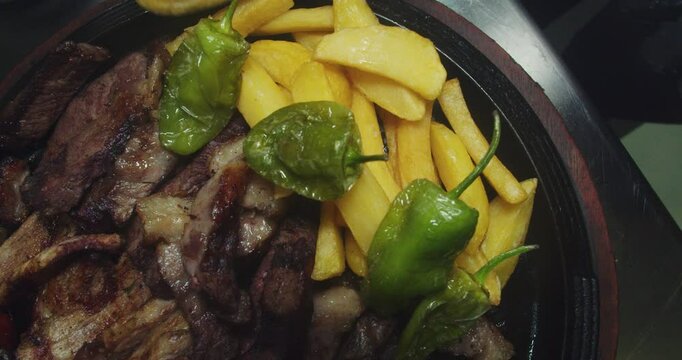 autiful slow motion shot of the hands of a chef wearing black rubber gloves as he places french fries on a Venezuelan grill plate inside a steakhouse kitchen.