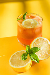 drink with lemon slices and basil leaves on a bright yellow surface