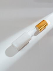 Cosmetic bottle with a gold lid on a white background with a sha