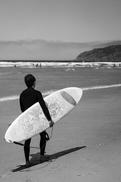 Surfer with surfboard going to surf in a beach.