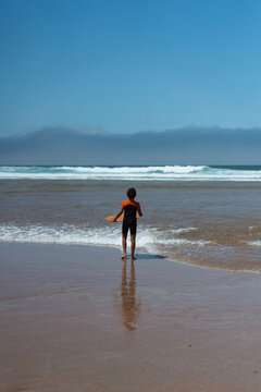 Young boy skim boarding in ocean.