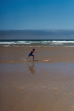 Young boy skim boarding in ocean.