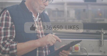 Using tablet, man in industrial setting with social media likes animation overlay - Powered by Adobe