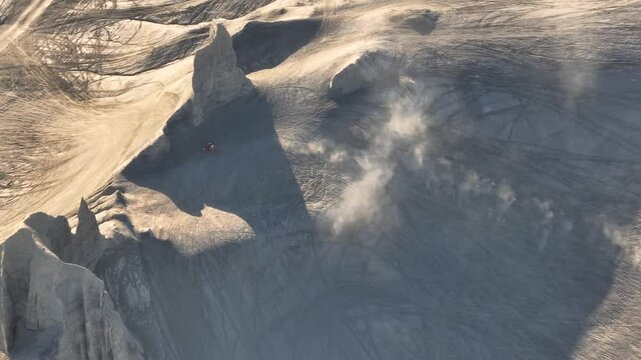 Aerial view of swing arm city with dust trails and rock formations in the desert landscape, Caineville, United States.