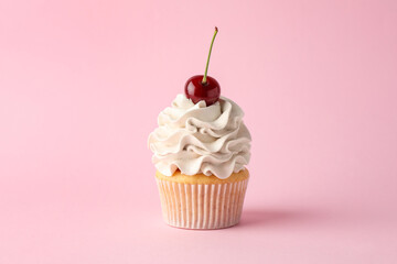 Delicious cupcake with cream and cherry on pink background