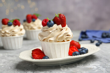 Tasty cupcakes with different berries on light grey table, closeup