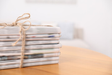 Stack of many newspapers in different languages on wooden table, space for text