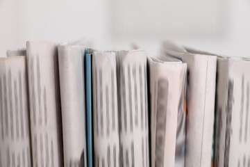 Many newspapers in different languages on blurred background, closeup