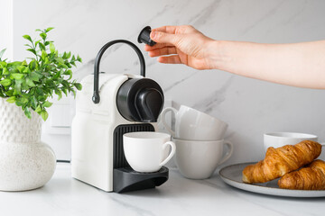 Person inserting coffee pod into white espresso machine