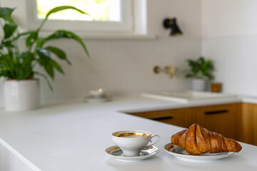A cozy morning in a bright kitchen featuring a cup of coffee and a fresh croissant