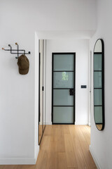 Modern hallway with glass door, minimalist coat rack and a round mirror in apartment