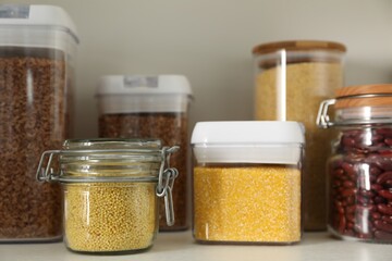 Different types of cereals and legumes in containers on white table, closeup