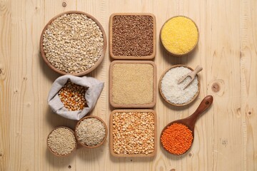 Different types of cereals and legumes on wooden table, flat lay