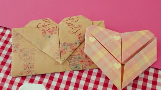 Two heart-shaped origami designs on pink and checkered backgrounds, showcasing delicate craftsmanship