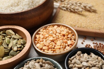 Different types of seeds and cereals in bowls on white table, closeup