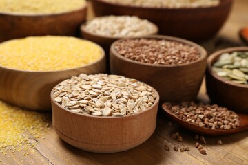 Different types of cereals and seeds on wooden table, closeup