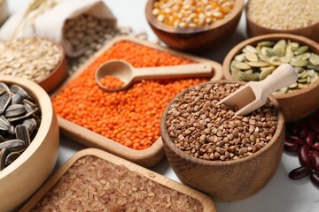 Different types of seeds, legumes and cereals on white table, closeup