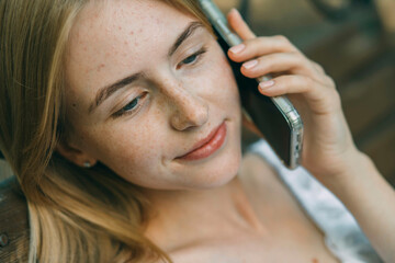 staying connected while enjoying the outdoors, girl with freckles is talking on her smartphone