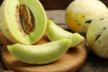Fresh whole and cut honeydew melons on wooden table, closeup
