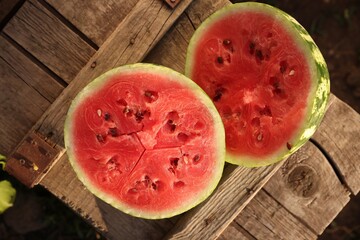 Halves of ripe watermelon on wooden crate outdoors, top view