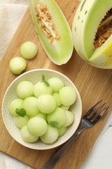 Melon balls in bowl and fresh fruit on white wooden table, top view