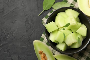Slices of yummy melon on dark table, flat lay. Space for text