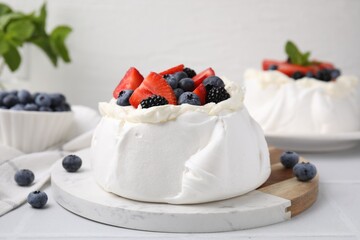 Pavlova cake (meringue dessert) with whipped cream and fresh berries on white table, closeup