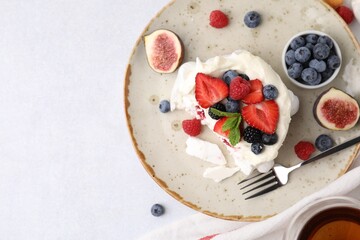 Pavlova cake (meringue dessert) with whipped cream, fresh berries, mint and fig on light table, top view. Space for text