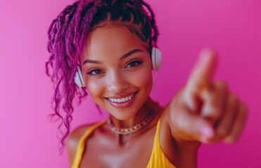 A purple haired woman dances, points at camera, on a magenta background, wearing yellow outfit.