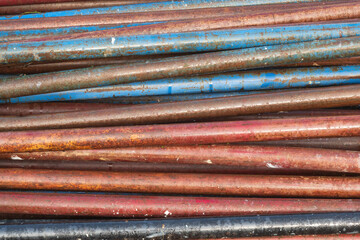 Many old marble pipes for scaffolding construction. Surface painted with different colors and covered with water drops. Background. Texture.