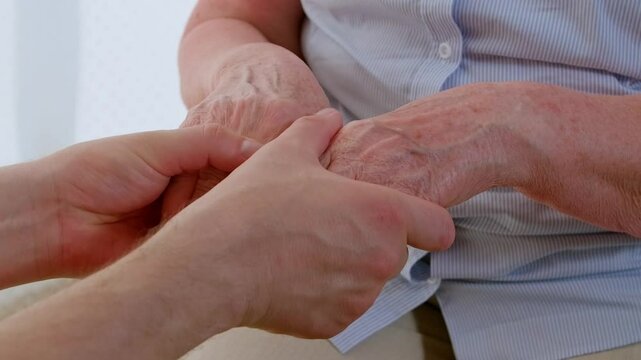 Parkinson disease and help of relatives. Man taking tremor hands of mother and calming her.