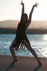 young woman passionately dancing on embankment with raised hands