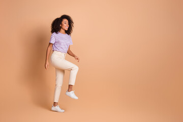 Full length profile portrait of pretty young woman walk climb empty space stairs wear t-shirt isolated on beige color background © deagreez