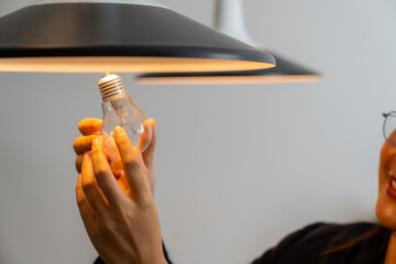 The young woman is replacing the incandescent bulb with an LED bulb