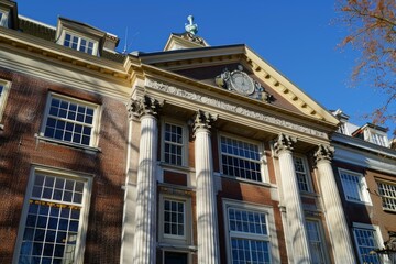 Obraz premium Traditional dutch building facade with white columns and a clock on a sunny day