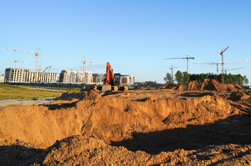 Excavator digging a foundation. Building construction. Tower Cranes on Residential Buildings construction. Excavator on groundwork on Construction site. Heavy construction equipment on excavation.