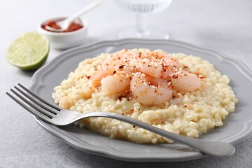 Delicious risotto with shrimps and cheese on light grey table, closeup