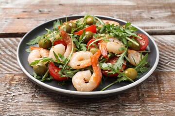 Delicious shrimp salad with tomato and olives on wooden table, closeup