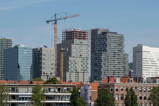 A vibrant scene showing mid-rise buildings under construction with prominent cranes highlighting development and urban growth set against a clear blue sky in Rotterdam Netherlans