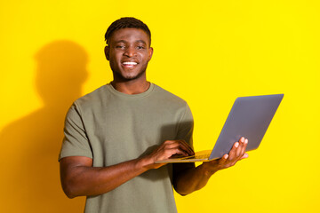 Photo of cheerful nice man wear trendy khaki clothes hold use modern netbook isolated on yellow color background