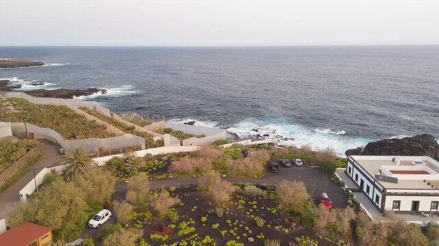 Aerial view of the scenic Faro de Punta Cumplida lighthouse surrounded by cliffs and banana trees overlooking the Atlantic Ocean, Lomo Machin, La Palma, Spain.