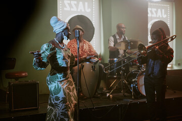 Group of four young African American jazz musicians giving concert in local bar