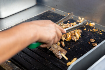 A person is cooking anticuchos on a grill