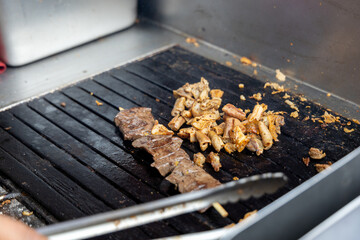 A person is cooking anticuchos on a grill