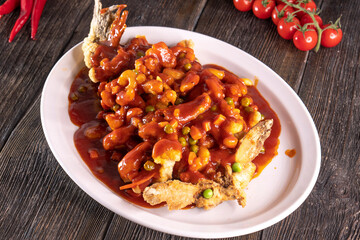 fried fish in sweet and sour sauce on wood table. Chinese food. food concept.
