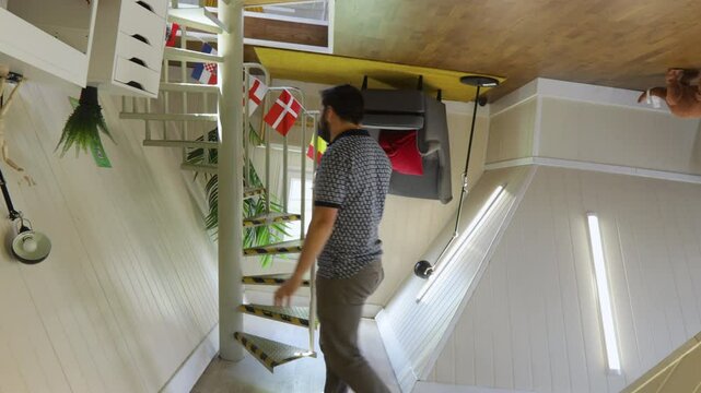 Man walking through a room with upside-down furniture in a quirky, illusionary house