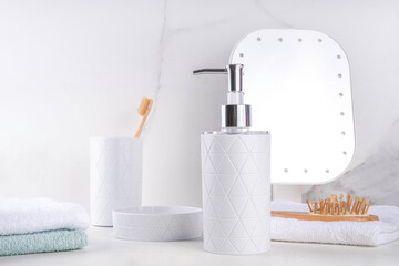 Naklejka premium Bathroom shelf simple white background. Dispenser for soap, shower gel, soap dish, glass with toothbrushes, stack of towels on countertop. Mockup for cosmetics, body care products, copy space