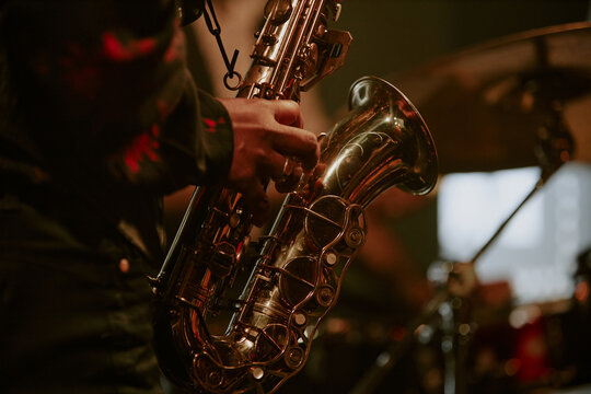 Medium closeup of unrecognizable Black jazz musician playing saxophone on stage in local bar